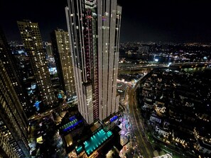 A high-rise building with a modern design, featuring vertical lines and illuminated windows. - Vinhomes Central Park - KIMI Residences (Ho Chi Minh City)