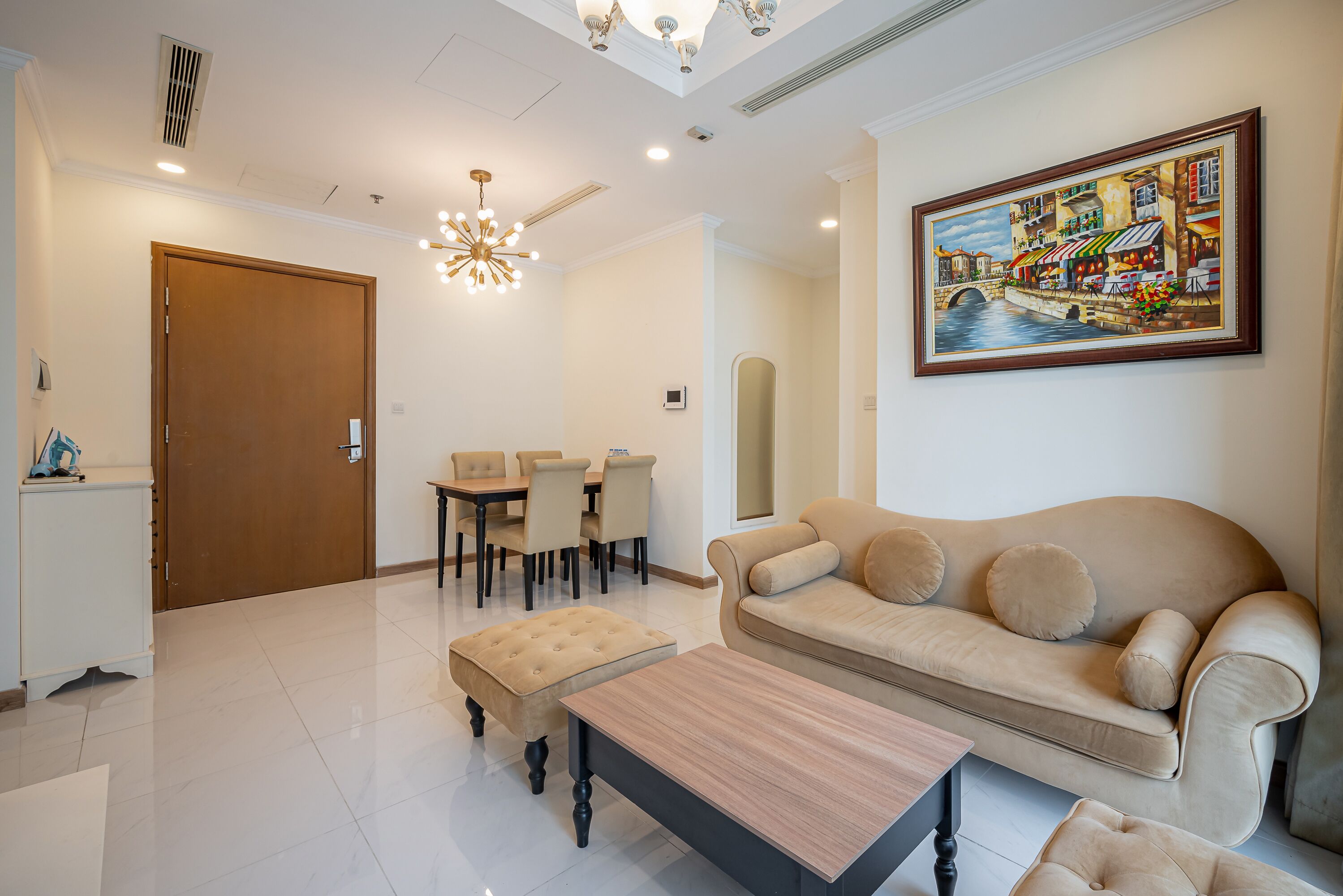 A spacious living room with a beige sofa, a wooden coffee table, and a dining area with a table and chairs.