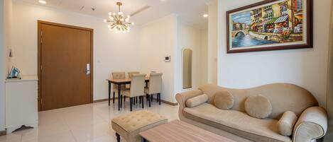 A spacious living room with a beige sofa, a wooden coffee table, and a dining area with a table and chairs.