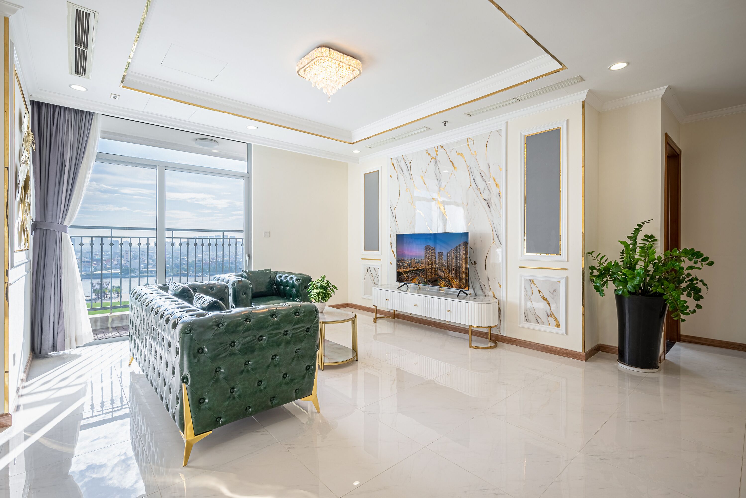 Un salón espacioso con un sofá verde, un televisor y un amplio ventanal con vistas a la ciudad.