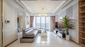 A modern living room with a sofa, TV, and a large window with curtains. - Vinhomes Central Park - KIMI Residences (Ho Chi Minh City)
