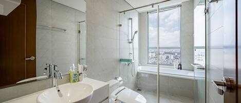 Un baño moderno con un espejo grande, un lavamanos, un inodoro y una ducha con mampara de vidrio.