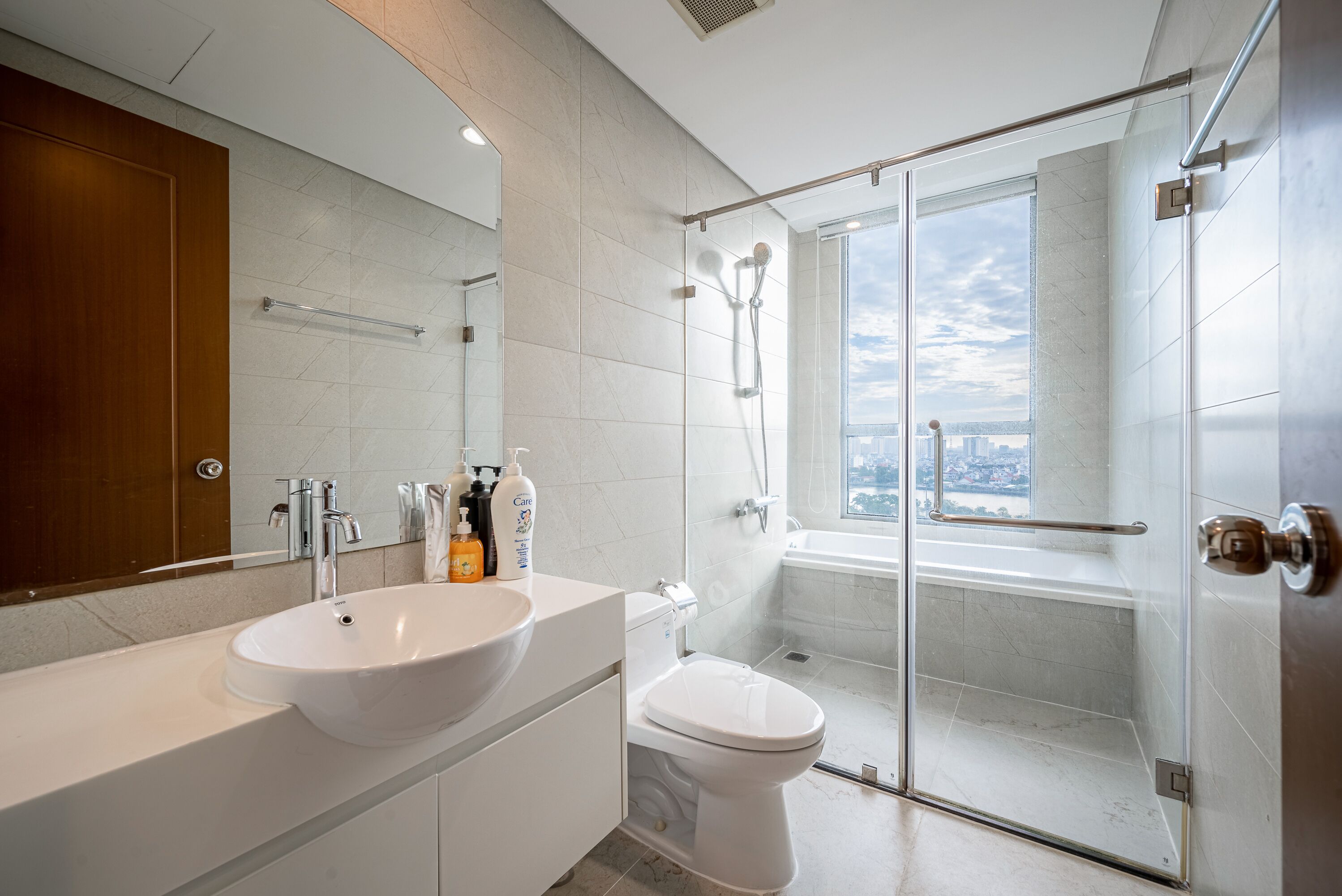 A modern bathroom with a large sink, toilet, and glass-enclosed shower.