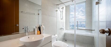 A modern bathroom with a large sink, toilet, and glass-enclosed shower.