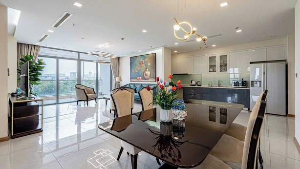 A modern living room with a dining area, large windows, and a kitchen. - Vinhomes Central Park - KIMI Residences (Ho Chi Minh City)
