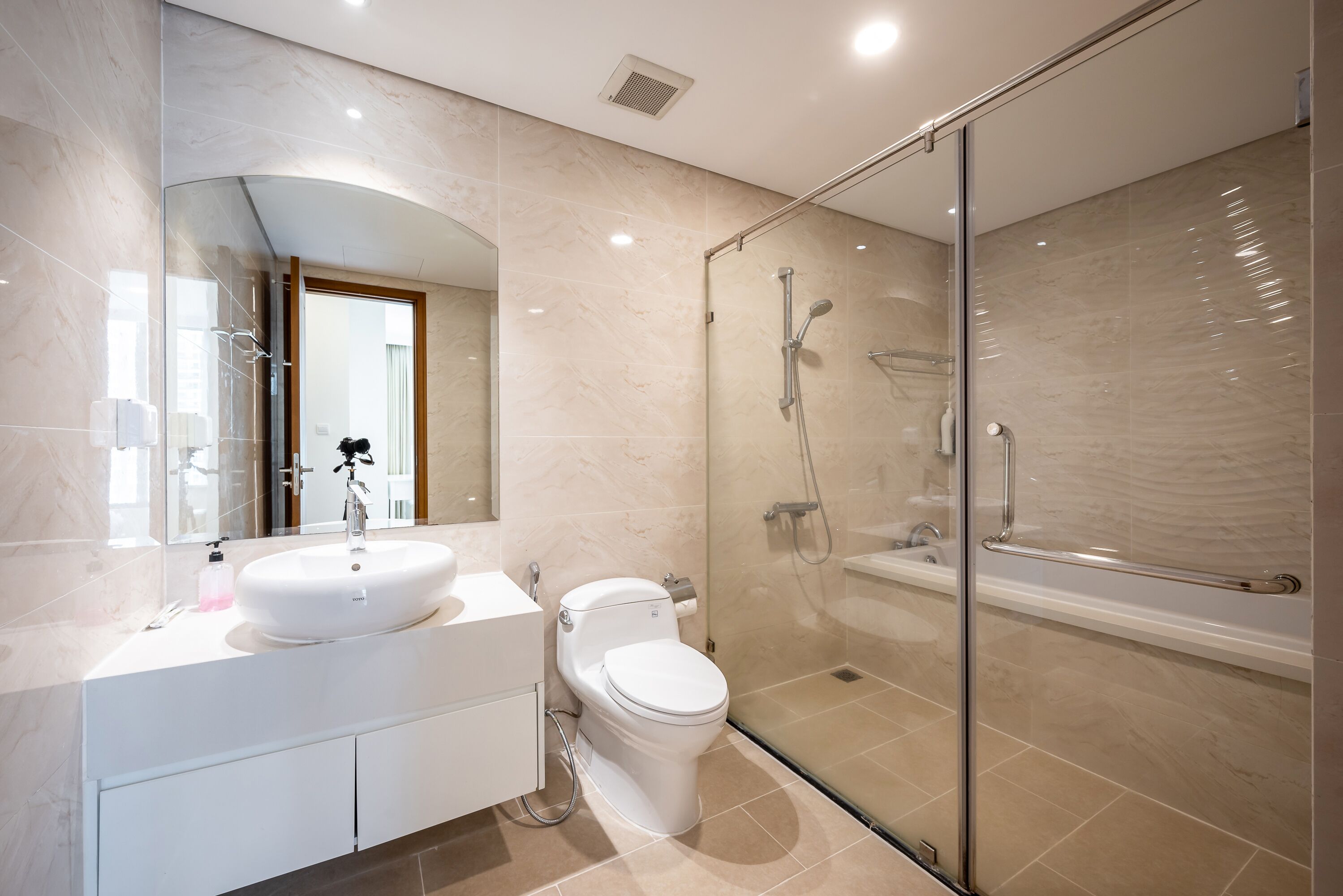 A modern bathroom with a glass-enclosed shower, a white sink, and a toilet.