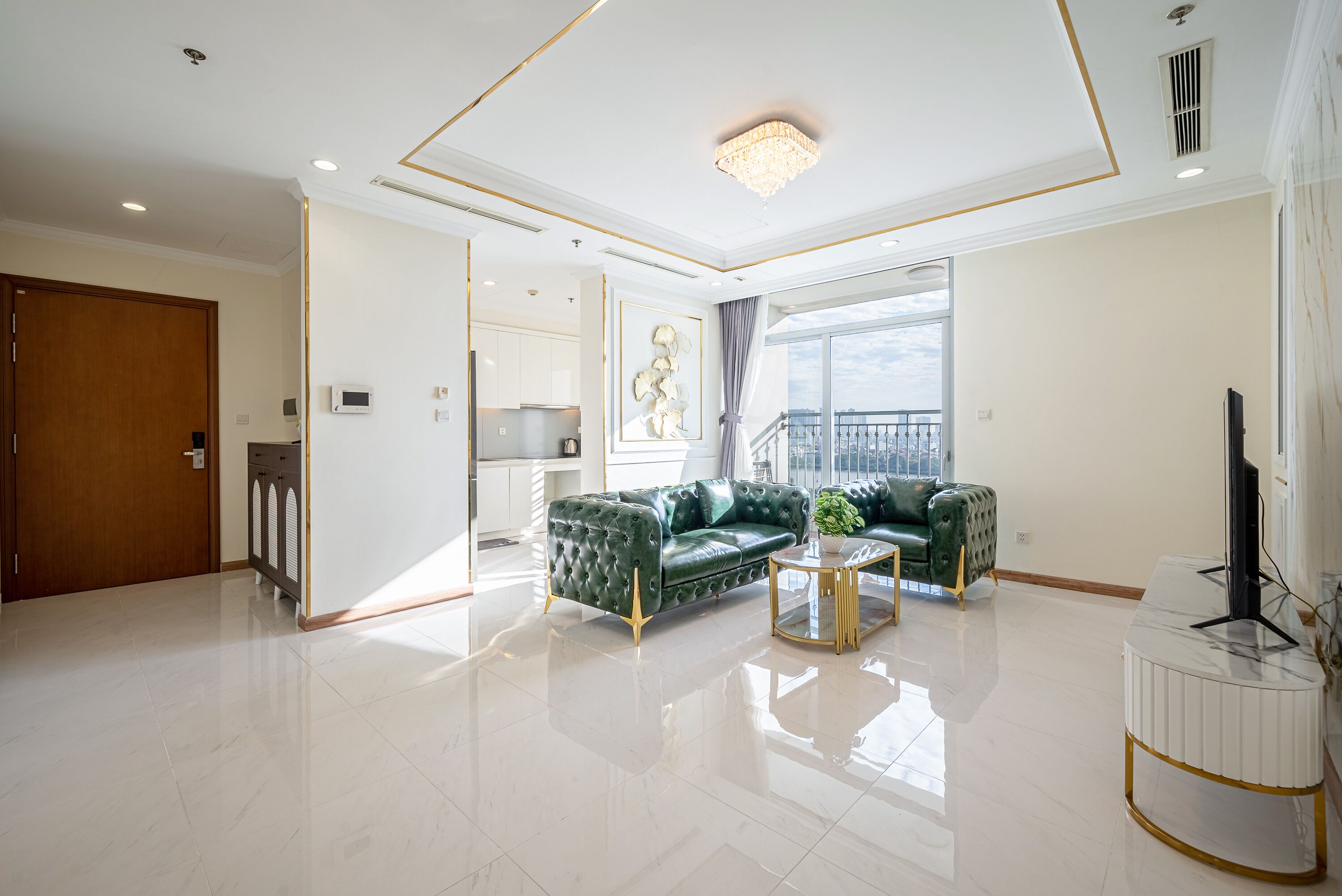 Un salón espacioso con un sofá de cuero verde, una mesita de centro redonda y un detalle decorativo de mármol blanco.