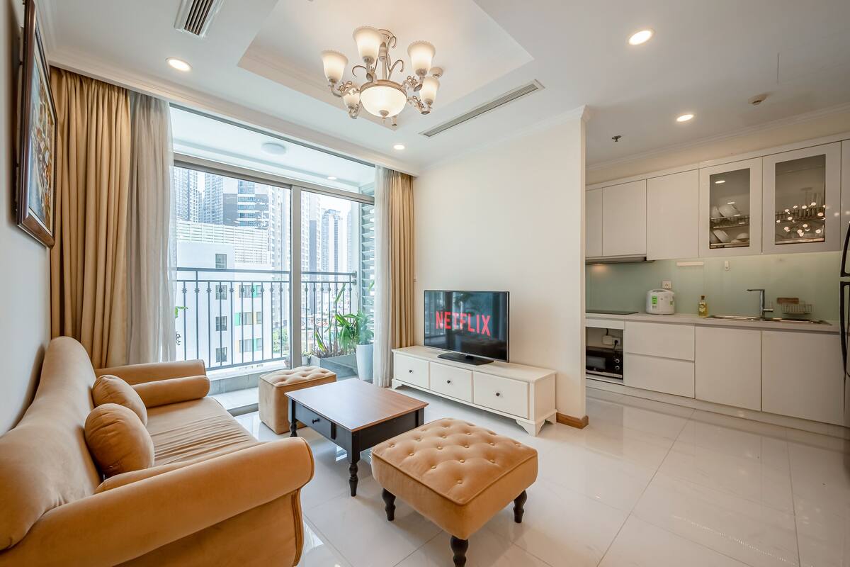 A modern living room with a sofa, ottoman, and a television displaying "NETFLIX".