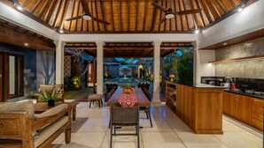 A spacious indoor area with a dining table, chairs, and a kitchen area. - Villa MD 2 Stylish 3 BR w/ Sunny Pool at Prime Eat Street (Badung)