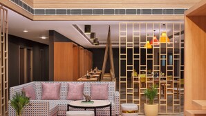 A modern living room with a sectional sofa, ottomans, a round table, and a decorative partition. - Ginger Nagpur Airport Road (Nagpur)