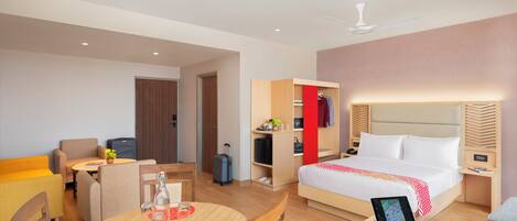 A modern hotel room with a bed, a desk, a chair, a table, and a wardrobe.