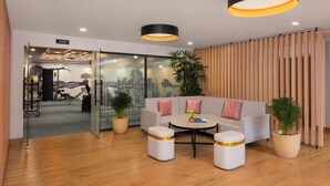 A modern office space with a patterned sofa, two round tables, and potted plants. - Ginger Nagpur Airport Road (Nagpur)