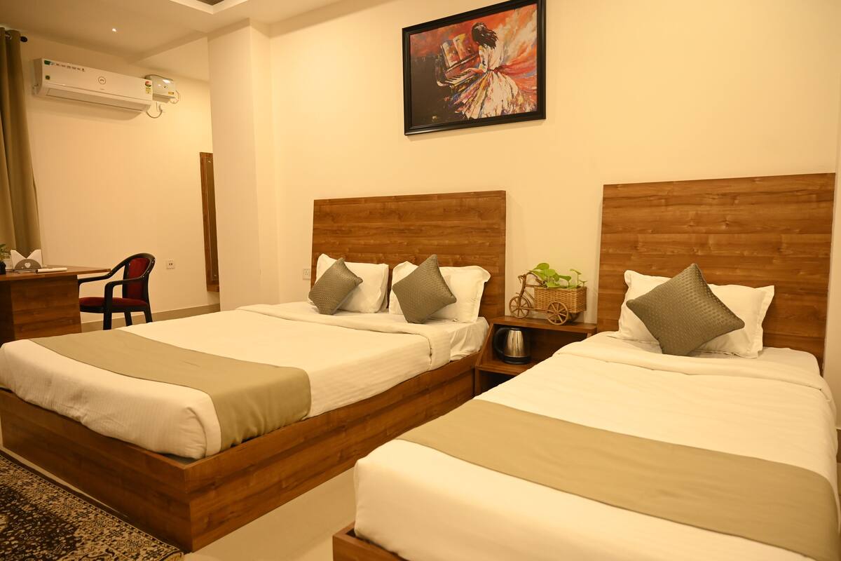 A hotel room with two beds, a desk, a chair, and a painting on the wall.