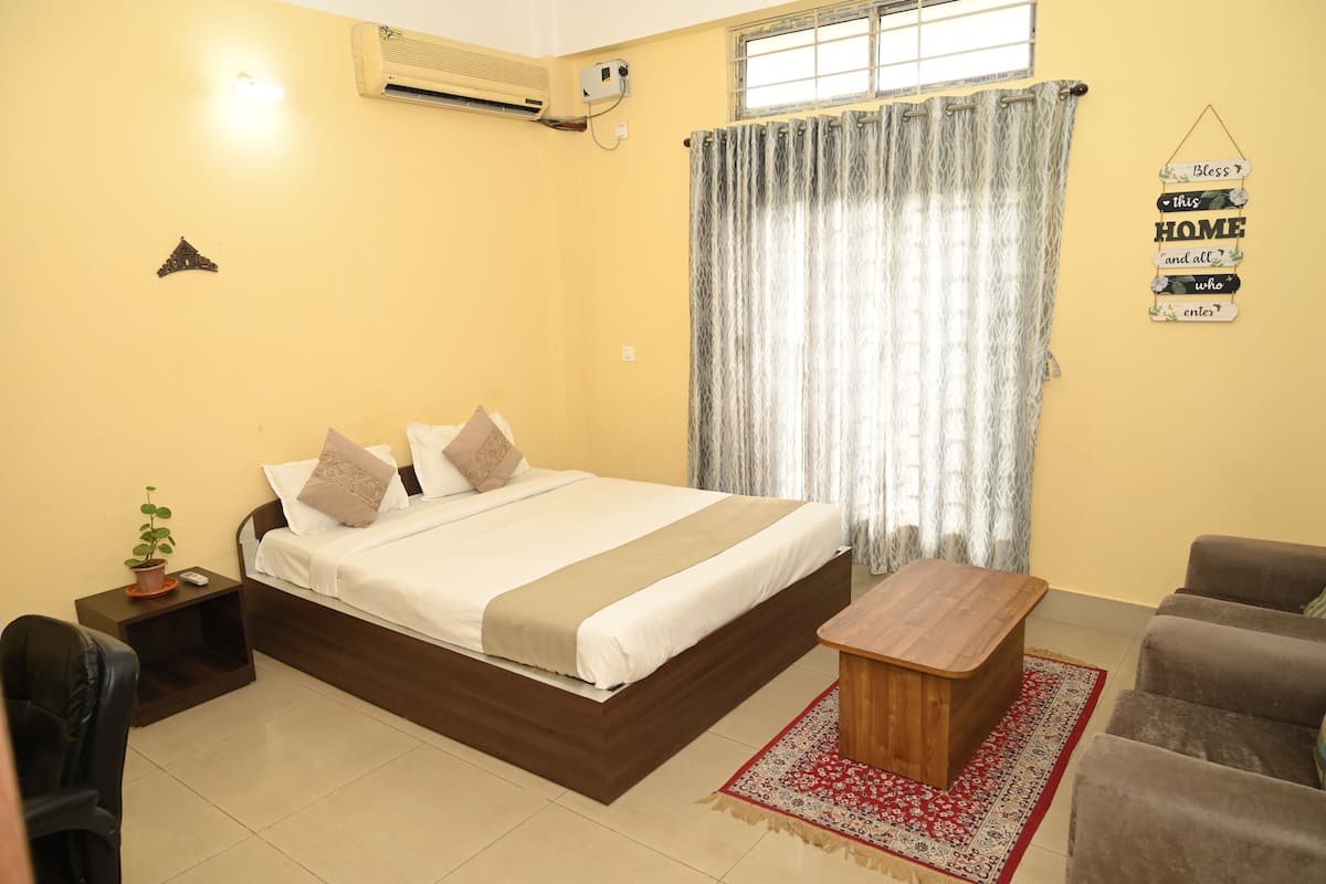 A bedroom with a bed, bedside table, chair, and a small table with a rug.