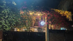 Una entrada cerrada con un letrero, rodeada de abundante follaje y plantas florecientes.