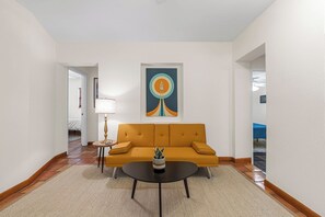 A modern living room with a sofa, a coffee table, and a painting on the wall.