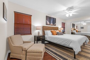 Ein Schlafzimmer mit Bett, Stuhl, Nachttisch, Lampe und Deckenventilator.