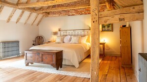 Un dormitorio con una cama de madera, una mesita de noche, un aparador y un radiador.