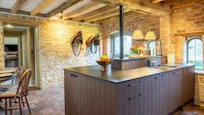 Una cocina con una isla grande, paredes de piedra y vigas de madera.