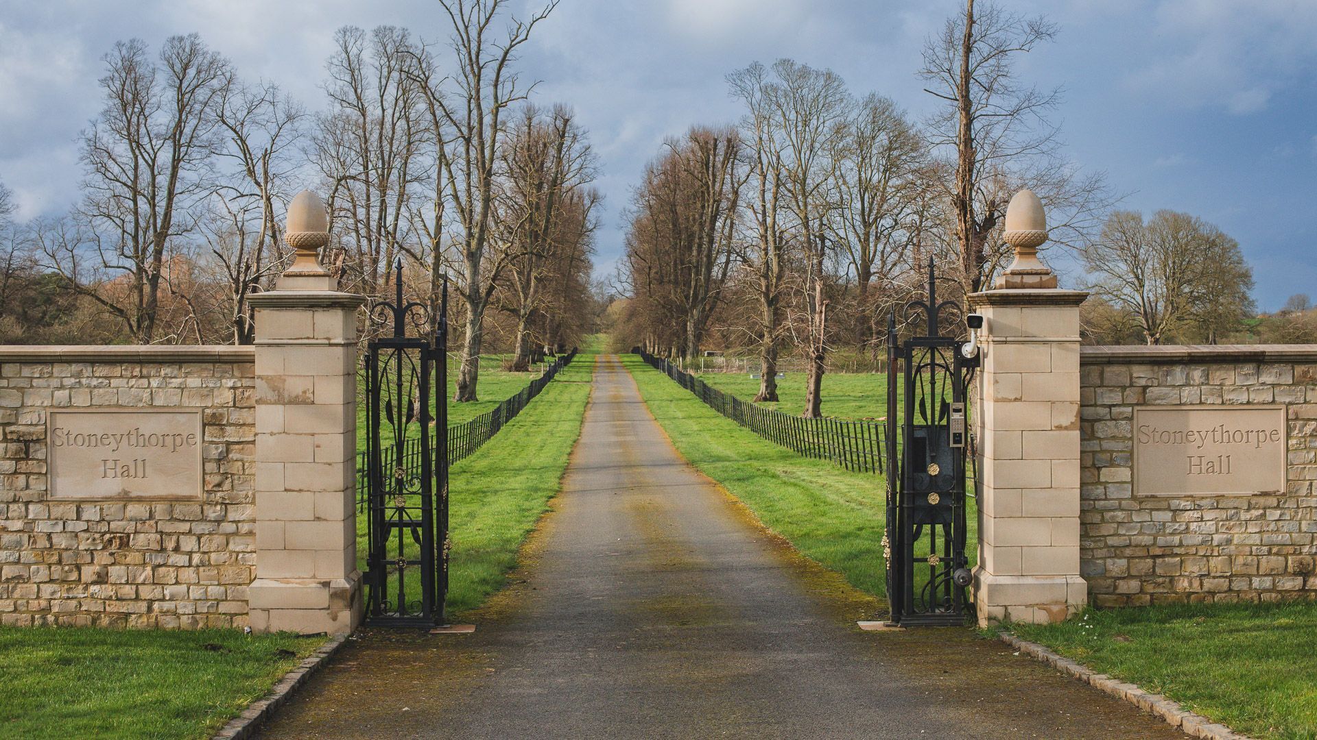 Un vialetto conduce a Stoneythorpe Hall, con mura in pietra e cancelli in metallo.