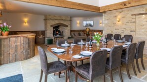 Un comedor con chimenea de piedra, vigas de madera y pared de piedra.