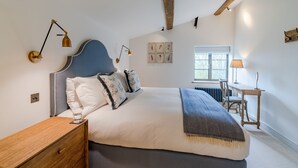 Un dormitorio con una cama grande, mesitas de noche, un escritorio y una ventana.