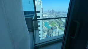 Een hoog gebouw met een glazen balkon met uitzicht op een stadsgezicht en een waterpartij.