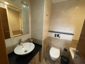 A modern bathroom with a white sink, a mirror, a toilet, and a shower. - Homes2Retreat 2Bedroom Apt Full Sea View (Dubai)