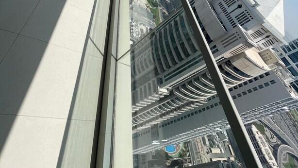 Een hoog gebouw met grote ramen en uitzicht op een stadsbeeld.