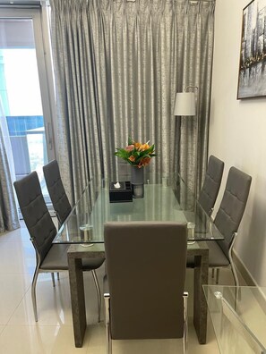 A conference room with a glass table, four chairs, a vase with flowers, and a lamp. - Homes2Retreat 2Bedroom Apt Full Sea View (Dubai)