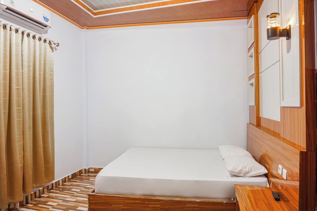 Un dormitorio pequeño y ordenado con una cama individual, cabecera de madera, mesita de noche y lámpara de pared.
