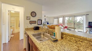 A kitchen with granite countertops, a stainless steel sink, and a dining area with a red couch and a TV. - Beech Mtn Studio < 1 Mi to Skiing: Bring Your Pet! (Beech Mountain)