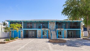 A two-story building with a blue exterior, a central staircase, and a paved driveway.
