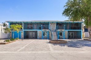 A two-story building with a blue exterior, a central staircase, and a paved driveway.