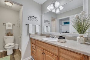 A bathroom with a wooden vanity, a large mirror, and a toilet.