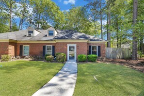 A two-story brick house with a front yard, a covered porch, and a small attached garage.