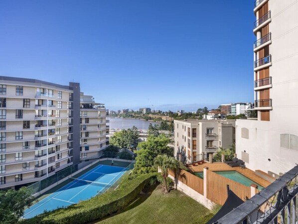 Un immeuble résidentiel doté de nombreux balcons, d’un court de tennis et d’un espace piscine.