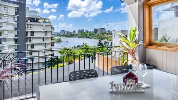 A balcony with a table, chairs, and a bottle of Rosalia wine. - Riverview casa/ walk to Mater & children hospital (South Brisbane)