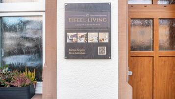 A sign for Eifeel Living Luxury Apartments with a QR code and photos of the interiors.