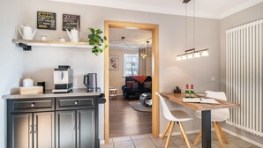 Una cocina moderna con cafetera, hervidor y una planta en la encimera.