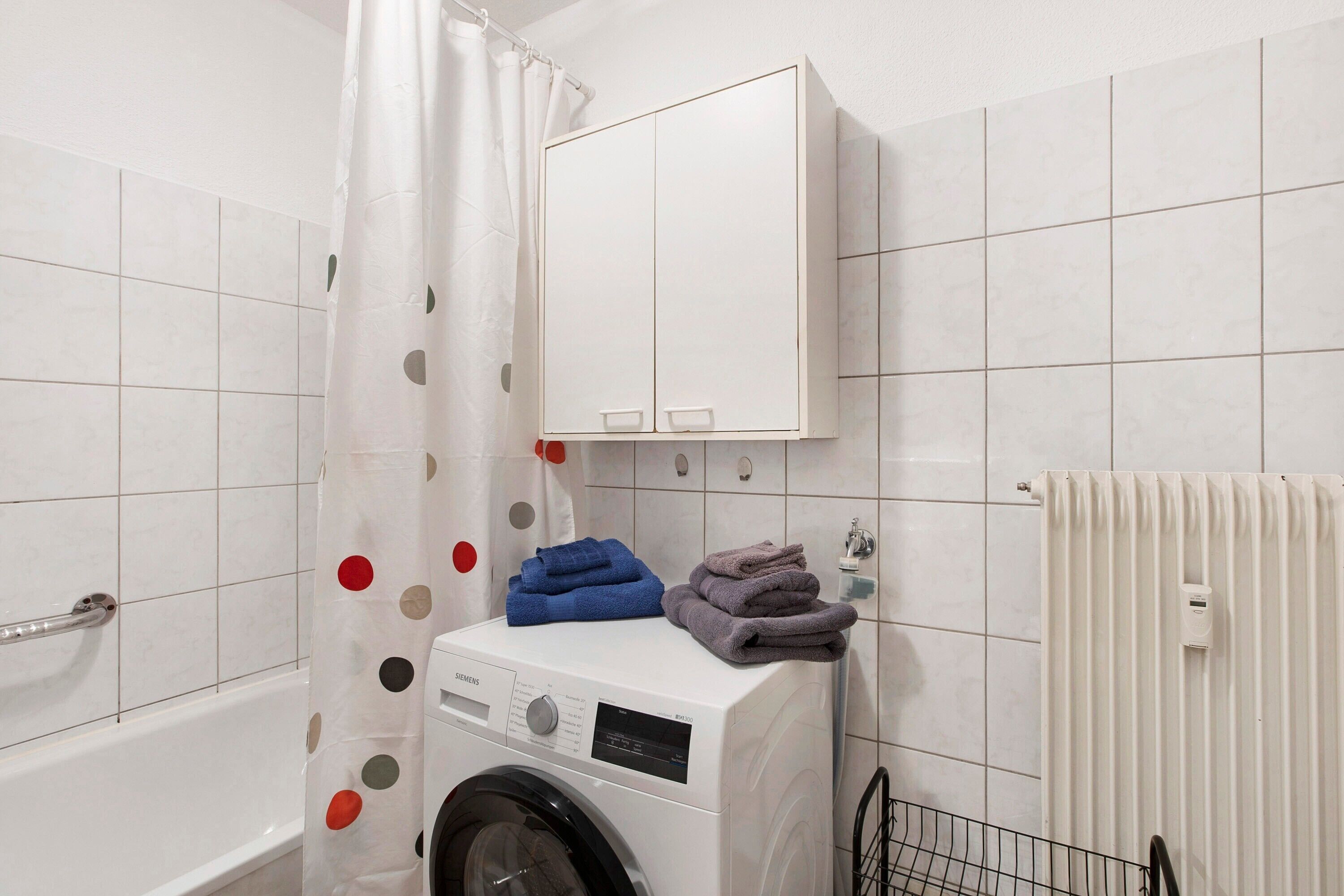 A laundry area with a washing machine, a drying rack, and a radiator.