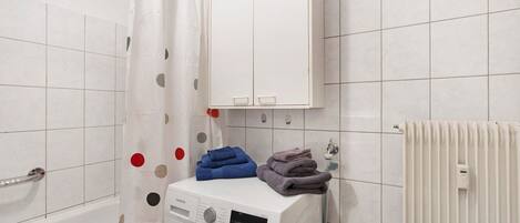 A laundry area with a washing machine, a drying rack, and a radiator.