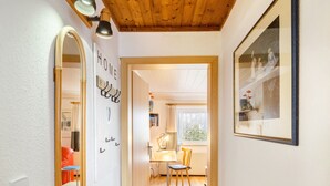 A hallway with a wooden ceiling, a mirror, a framed picture, and a desk with a chair. - Apartment 'Djuren' with Private Terrace, Shared Garden, and Wi-Fi (Niedersachsen - Emden)