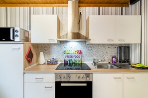 A kitchen with white cabinets, a stainless steel range hood, a microwave, and a sink. - Apartment 'Djuren' with Private Terrace, Shared Garden, and Wi-Fi (Niedersachsen - Emden)