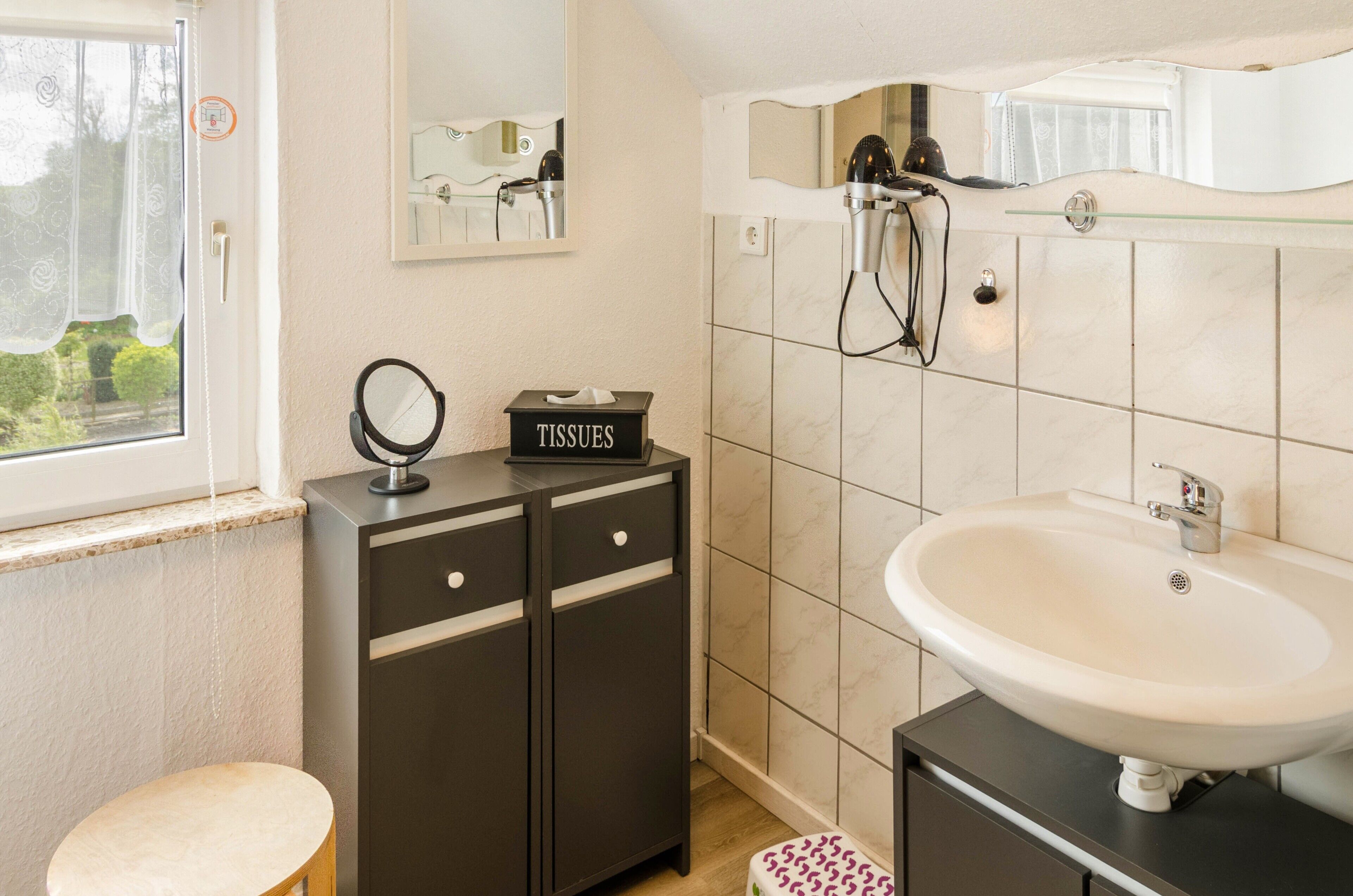 A bathroom with a sink, mirror, and toiletries cabinet.
