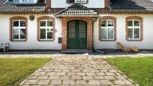 A two-story building with a brick facade, a green door, and a tiled roof.