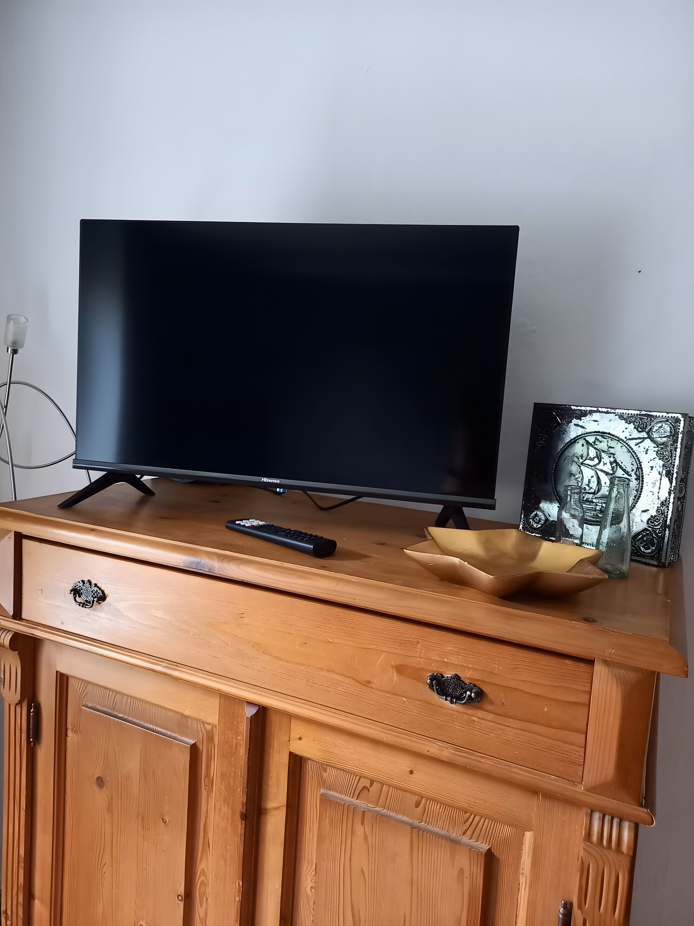 Un mueble bajo de madera con un televisor de pantalla plana, un control remoto y objetos decorativos.