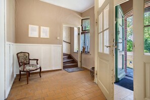 A room with a chair, a staircase, and a door leading outside. - Villa 'Ferienhaus Sommer Linden' with Private Terrace, Private Garden and Wi-Fi (Deyelsdorf)
