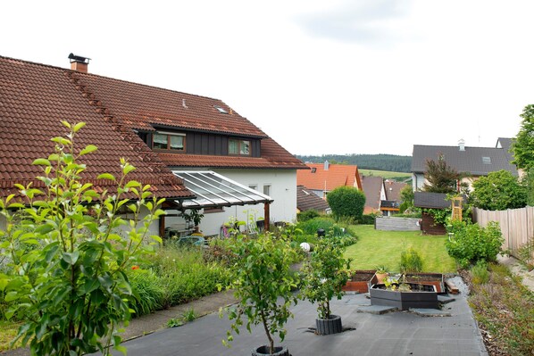 A residential backyard with a house, a garden, and a patio area.