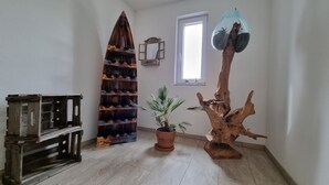 Una habitación con un banco de madera, una estantería para vinos de madera, una planta en maceta, una escultura de tronco de árbol y un espejo en la pared.